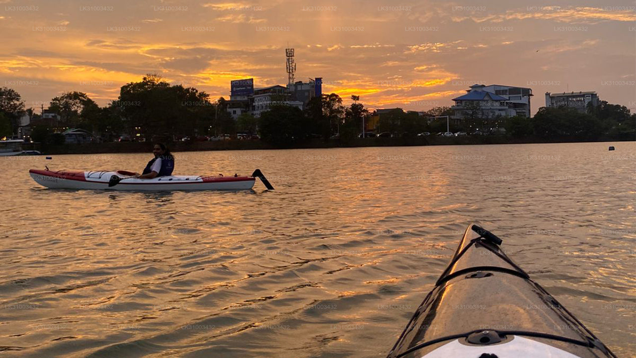 Kayakers on a lake at sunset with city skyline in the background
