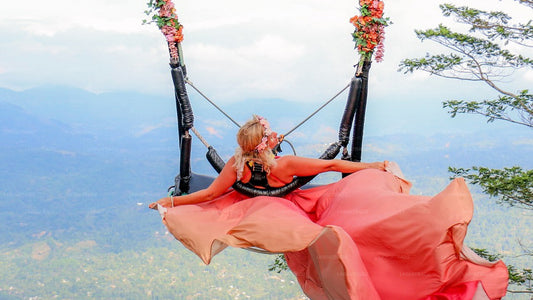 Woman in a red dress on a swing with a scenic background